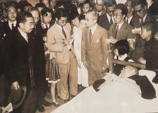 担架に横たわる永井隆と、そのそばに立つ昭和天皇